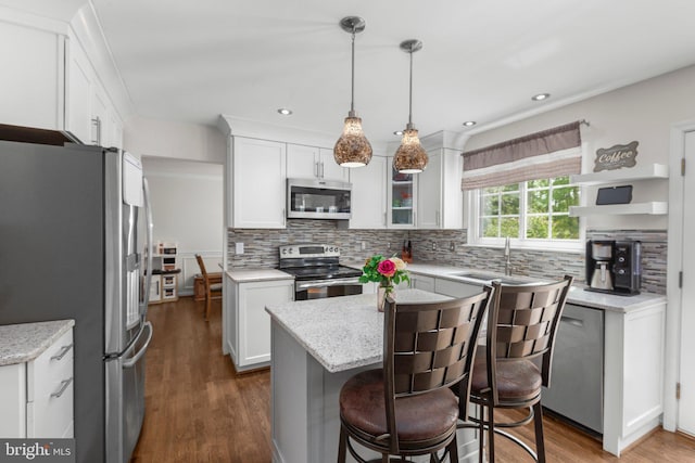 kitchen featuring tasteful backsplash, stainless steel appliances, a kitchen island, and a sink