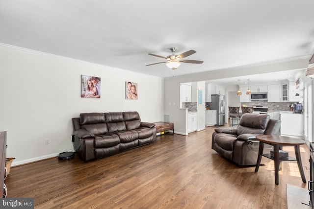 living area featuring ornamental molding, ceiling fan, wood finished floors, and baseboards