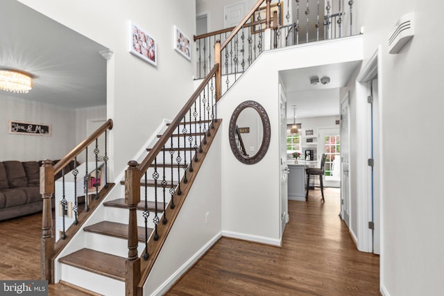 stairs featuring baseboards, wood finished floors, and a towering ceiling
