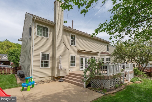 rear view of property with a chimney, fence, a deck, and a patio