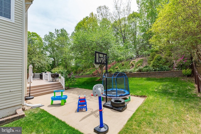 view of yard featuring a deck, a patio, and a trampoline