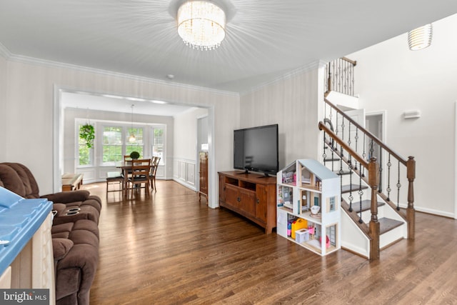 living room with ornamental molding, wood finished floors, a notable chandelier, and stairs