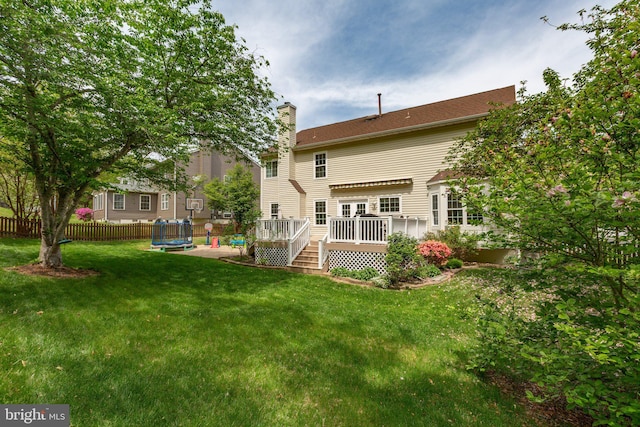 back of house featuring a deck, a yard, fence, and a chimney