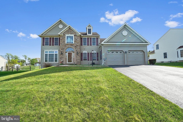 colonial house with fence, an attached garage, stone siding, a front yard, and driveway