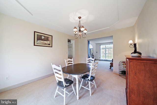 dining space featuring baseboards, light carpet, and a chandelier
