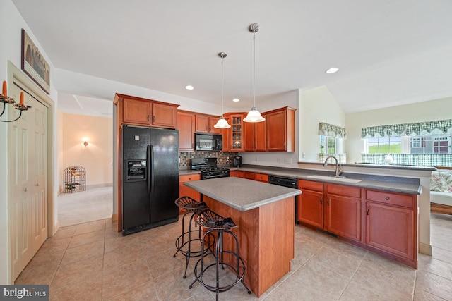 kitchen featuring a breakfast bar area, a sink, black appliances, a peninsula, and glass insert cabinets