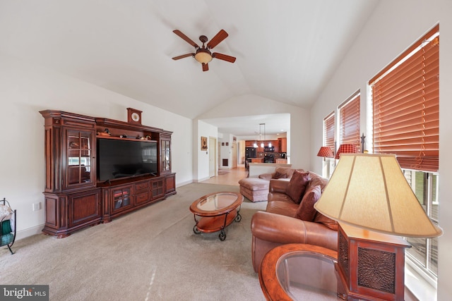 living room with baseboards, carpet flooring, ceiling fan with notable chandelier, and vaulted ceiling