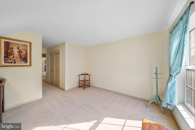 empty room with carpet floors, baseboards, and lofted ceiling