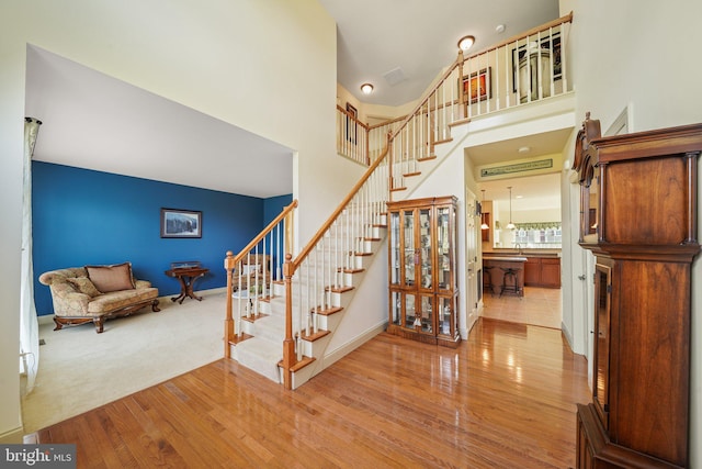 stairs with a high ceiling and wood finished floors