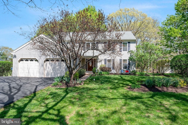 colonial inspired home featuring a front lawn, a garage, and aphalt driveway