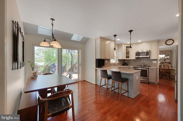 kitchen with dark wood-style floors, light stone countertops, a peninsula, and appliances with stainless steel finishes