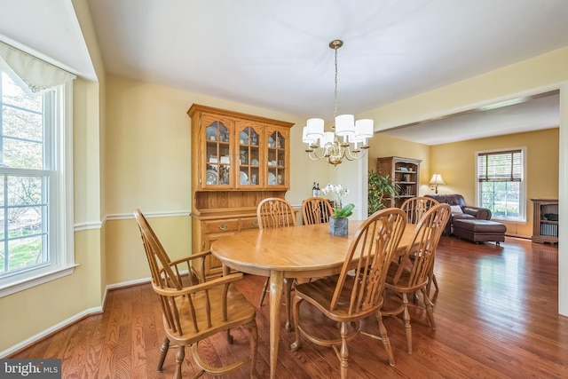 dining room featuring wood finished floors, a chandelier, and baseboards