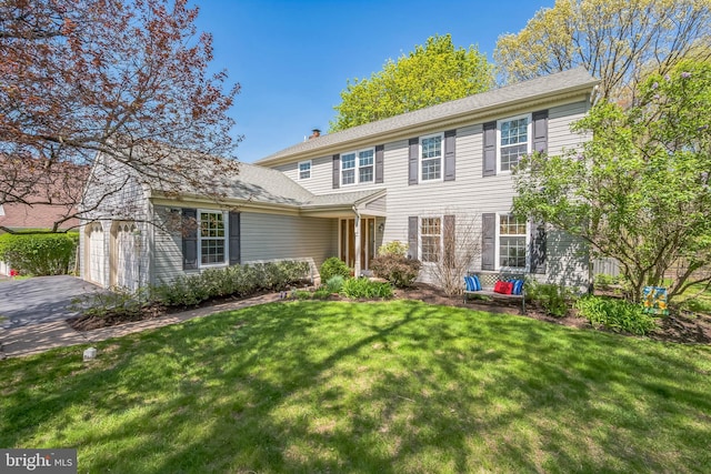 view of front of home featuring a chimney, a front lawn, and driveway