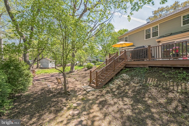 view of yard featuring an outbuilding, a deck, a storage unit, and stairway