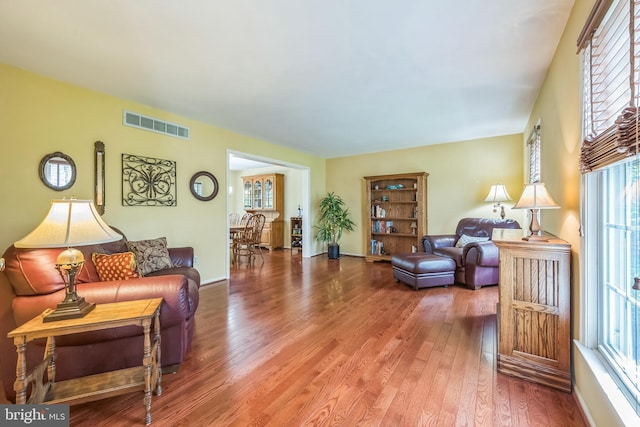 living room featuring visible vents, wood finished floors, and plenty of natural light