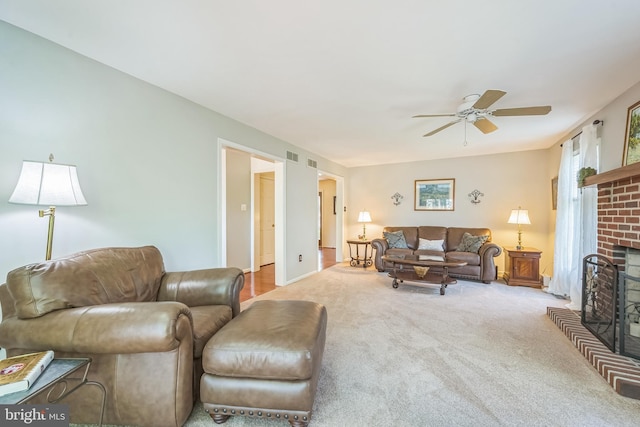 carpeted living room with a brick fireplace, a ceiling fan, and visible vents