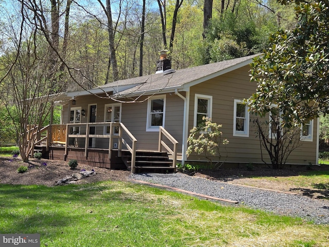 back of house featuring a chimney, a shingled roof, and a yard