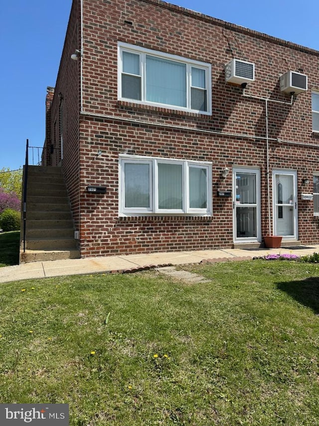 back of property with a lawn and brick siding