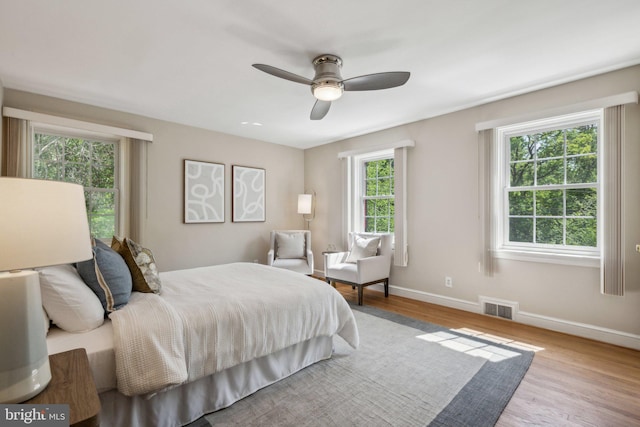 bedroom with ceiling fan, baseboards, visible vents, and wood finished floors