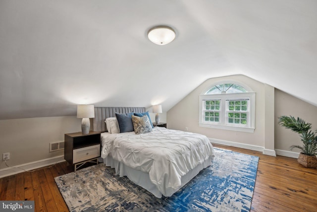 bedroom featuring baseboards, lofted ceiling, hardwood / wood-style floors, and visible vents