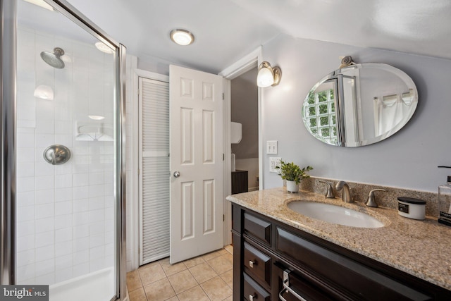 bathroom featuring vaulted ceiling, vanity, tile patterned flooring, and a shower stall