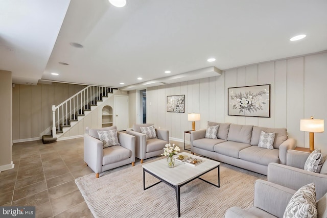 living room with tile patterned flooring, stairway, baseboards, a decorative wall, and recessed lighting