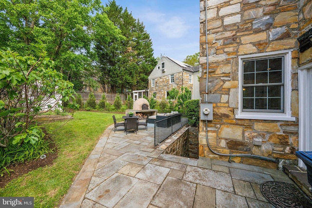 view of patio with fence and an outdoor living space with a fireplace