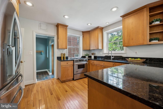 kitchen with open shelves, light wood-style floors, dark stone counters, a sink, and stainless steel appliances