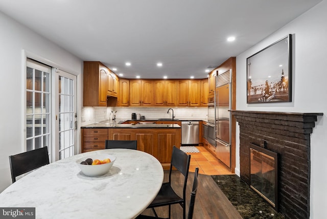913 Spruce St, Philadelphia, PA 19107 - kitchen with stainless steel appliances, a sink, tasteful backsplash, a brick fireplace, and brown cabinets