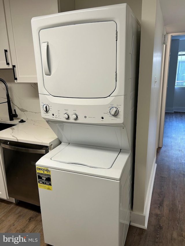 laundry room with stacked washer / drying machine, wood finished floors, and baseboards