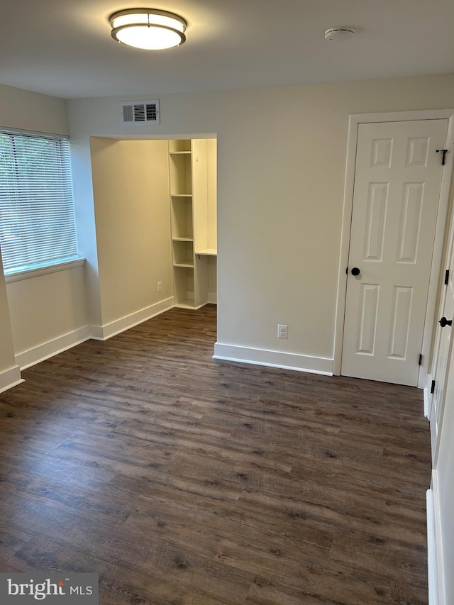 unfurnished room featuring baseboards, dark wood-style flooring, and a smoke detector