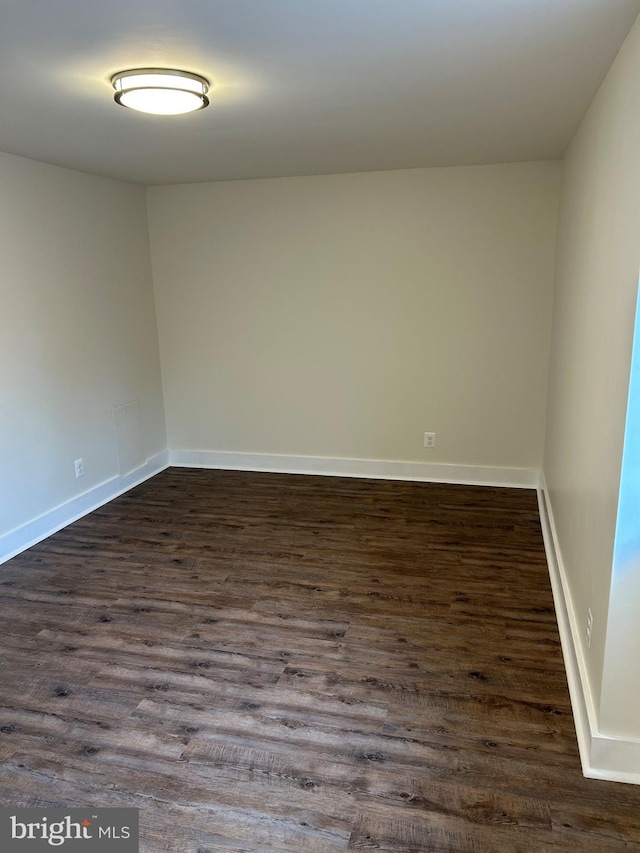 spare room with dark wood finished floors and baseboards