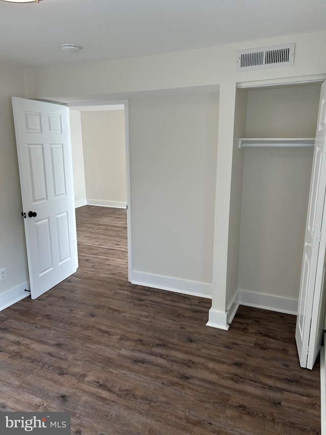 unfurnished bedroom featuring dark wood-style flooring, baseboards, and a closet