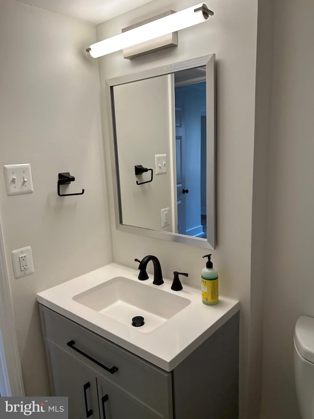 half bathroom featuring vanity and toilet