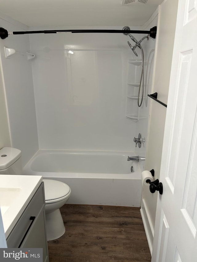 bathroom featuring toilet, wood finished floors, vanity, and tub / shower combination