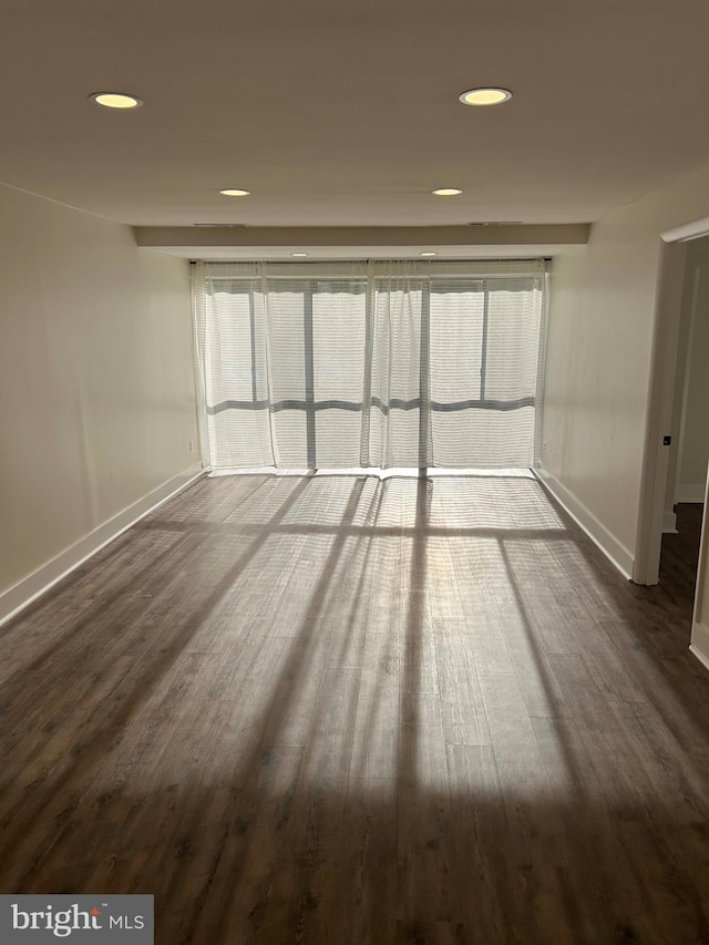 empty room featuring baseboards, dark wood-style flooring, healthy amount of natural light, and recessed lighting