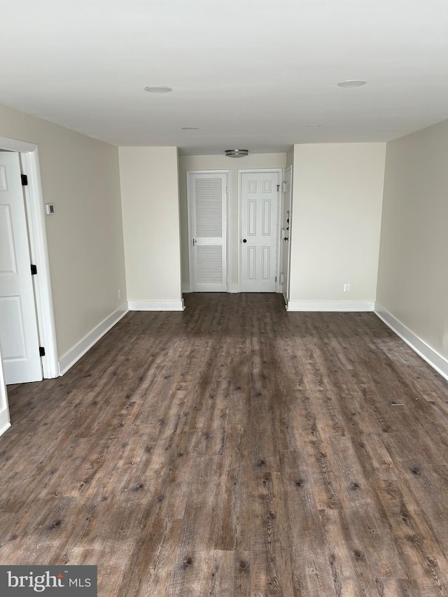 empty room with dark wood-style flooring and baseboards