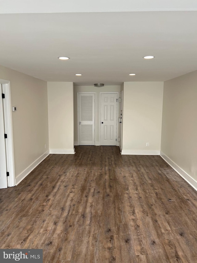 spare room with baseboards, dark wood finished floors, and recessed lighting