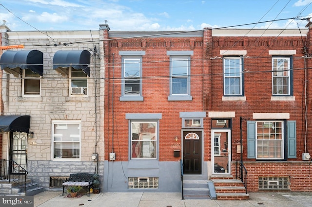 townhome / multi-family property with cooling unit, brick siding, and stone siding