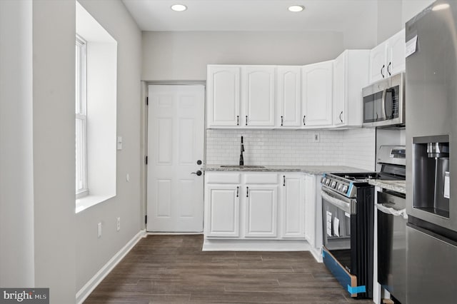 kitchen featuring a sink, backsplash, light stone counters, white cabinets, and appliances with stainless steel finishes