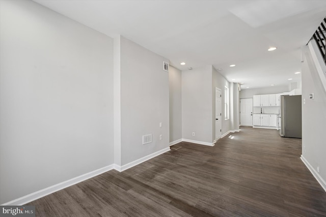 spare room with dark wood finished floors, baseboards, visible vents, and recessed lighting