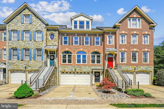 multi unit property featuring a garage, stairs, driveway, and stone siding