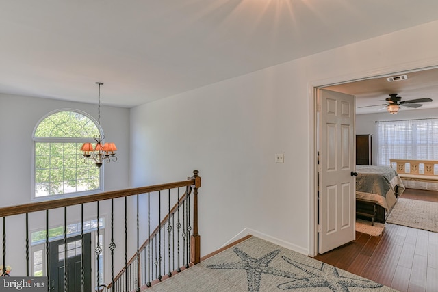 hallway featuring plenty of natural light, dark wood-style flooring, visible vents, and a chandelier