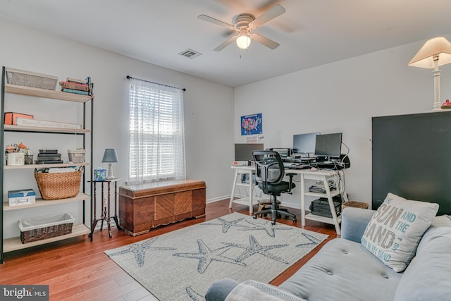 office space featuring visible vents, a ceiling fan, baseboards, and wood finished floors