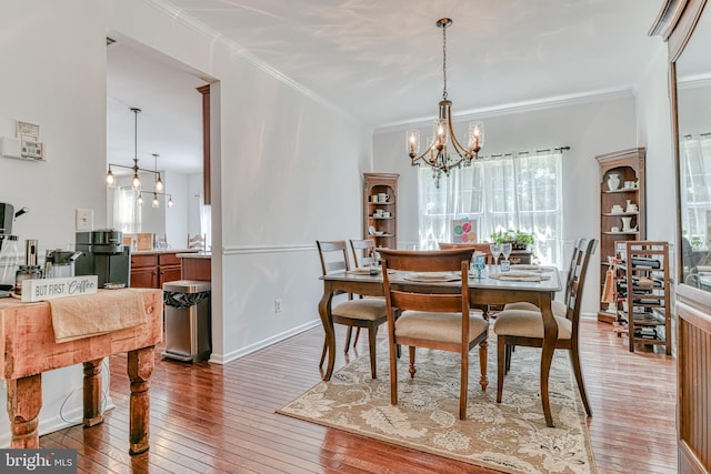 dining space featuring an inviting chandelier, ornamental molding, and hardwood / wood-style flooring