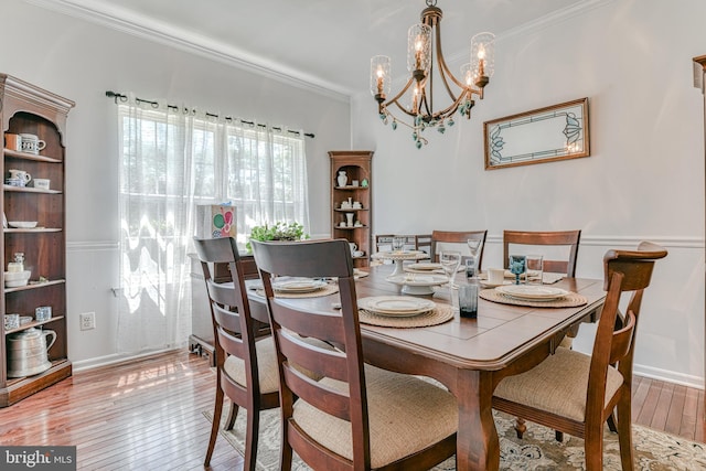 dining space featuring baseboards, an inviting chandelier, ornamental molding, and hardwood / wood-style floors