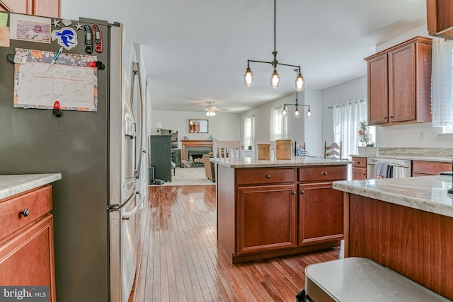 kitchen featuring a fireplace, a ceiling fan, stainless steel appliances, and light wood finished floors