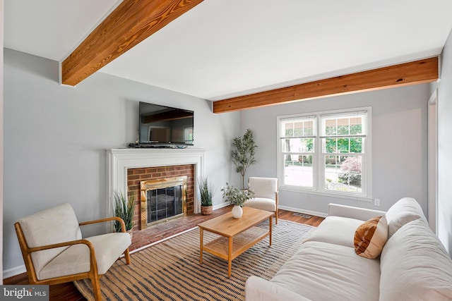 living room with wood finished floors, visible vents, a brick fireplace, beamed ceiling, and baseboards