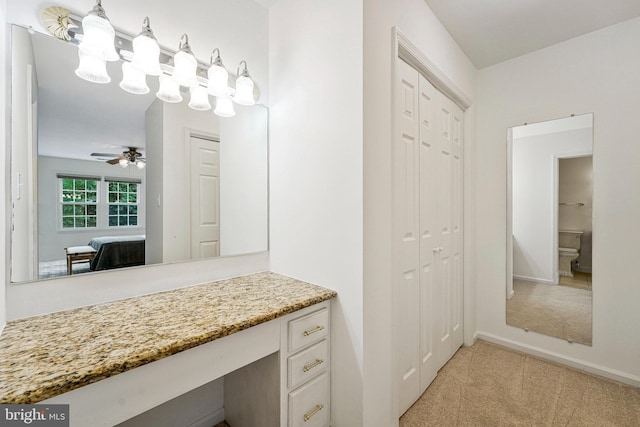 ensuite bathroom featuring a closet, vanity, ceiling fan, connected bathroom, and baseboards