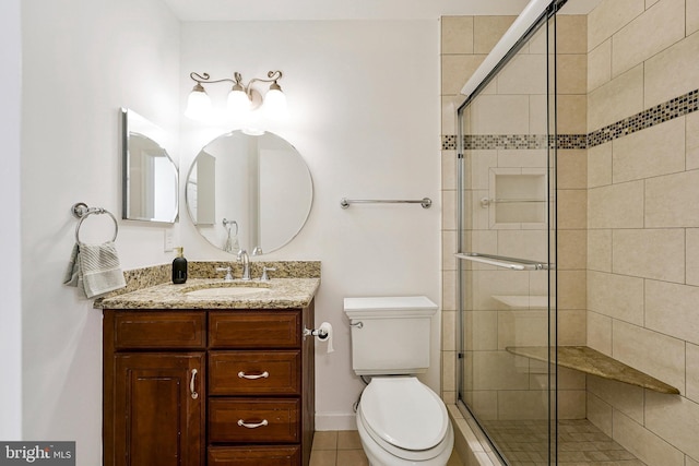bathroom featuring vanity, toilet, a shower stall, and tile patterned floors